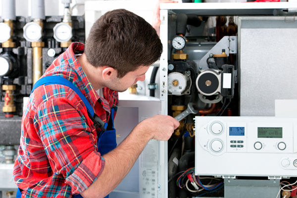 HVAC technician inspecting and repairing boiler controls in Fort Collins