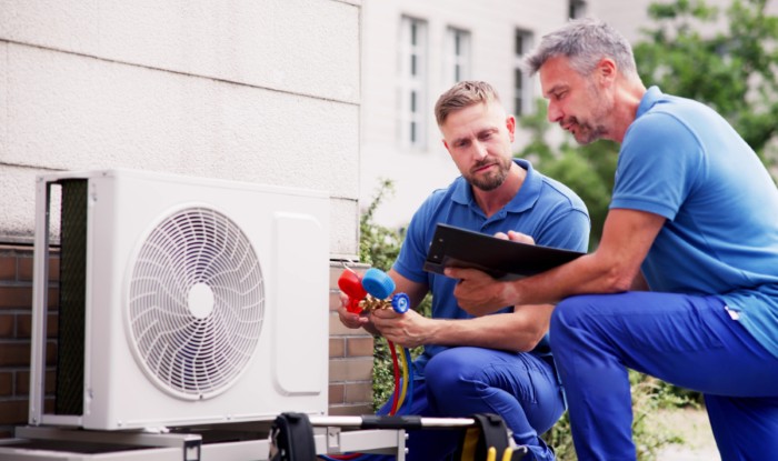 HVAC technicians installing an outdoor air conditioning unit in Fort Collins