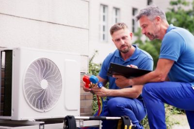 HVAC technicians reviewing an outdoor air conditioning unit in Fort Collins, CO