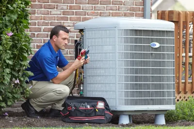 HVAC technician inspecting an outdoor air conditioning unit in Fort Collins, CO